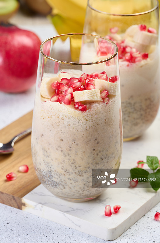 一杯加入了香蕉块和石榴籽的奇亚籽酸奶甜点图片素材