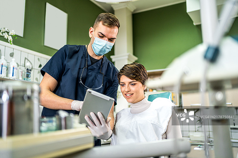 牙医在平板电脑上向患者展示X光片图片素材