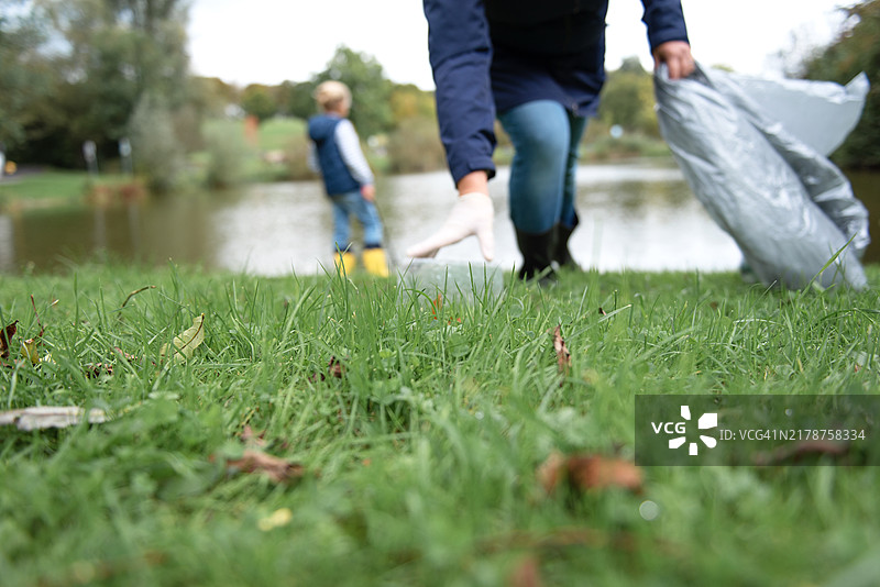 母亲和她的儿子在湖岸边捡垃圾图片素材