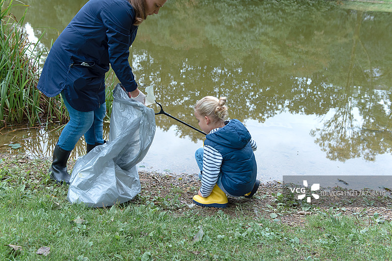 母亲和她的儿子在湖岸边捡垃圾图片素材
