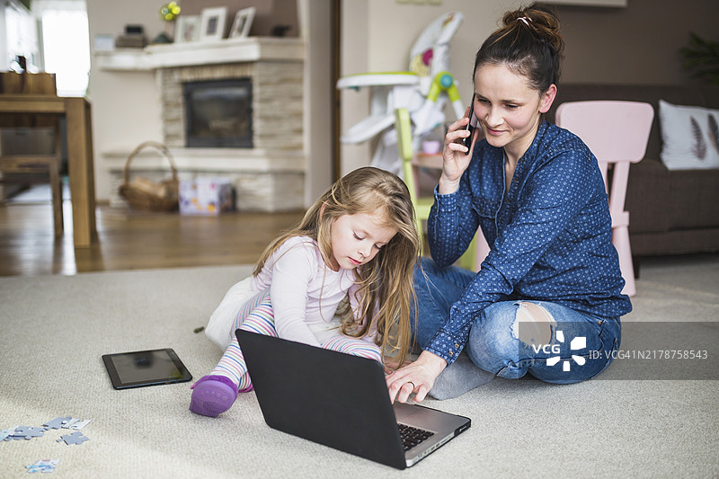 女人和女儿一起用笔记本电脑和手机图片素材