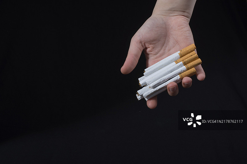 在黑色背景上手里拿着一包香烟图片素材
