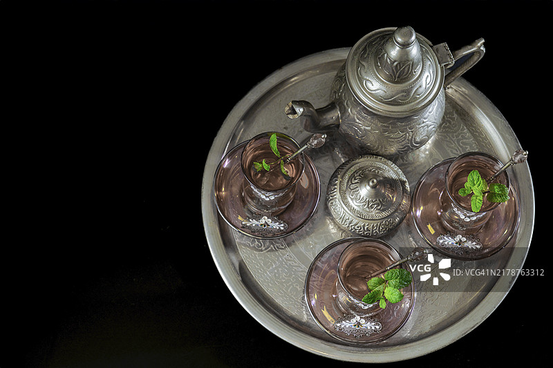 传统摩尔薄荷茶具的俯视图，托盘上放着装饰精美的玻璃器皿、银茶壶和糖罐图片素材