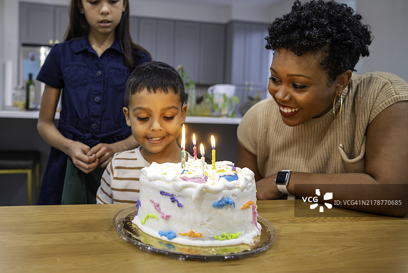 年轻的多种族幸福可爱的家庭在家中与两个孩子一起庆祝生日图片素材