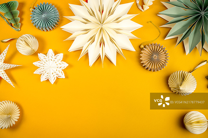 黄色背景上的纸雪花和圣诞树装饰品图片素材