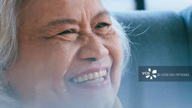 快乐的眼睛。特写肖像，一位快乐的老年女性微笑着。图片素材