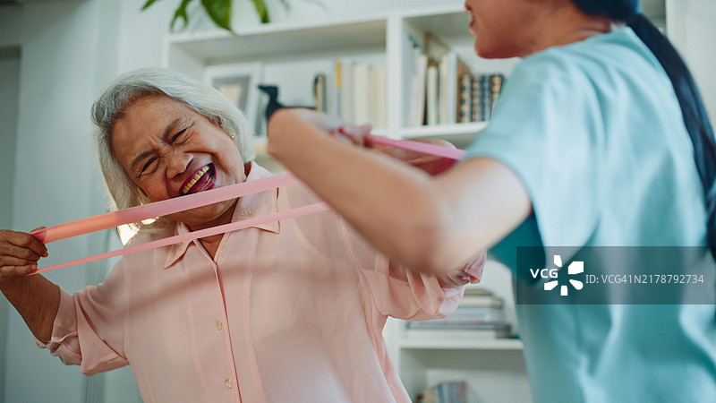 护士物理治疗师在家中鼓励老年女性锻炼。图片素材