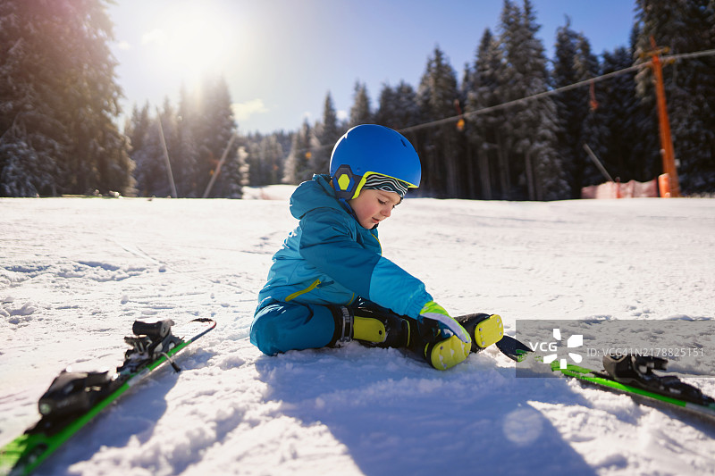 男孩在准备滑雪坡道时调整他的滑雪靴图片素材