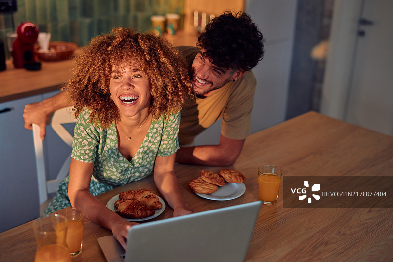 快乐的夫妇在家中使用笔记本电脑享受休闲时光图片素材