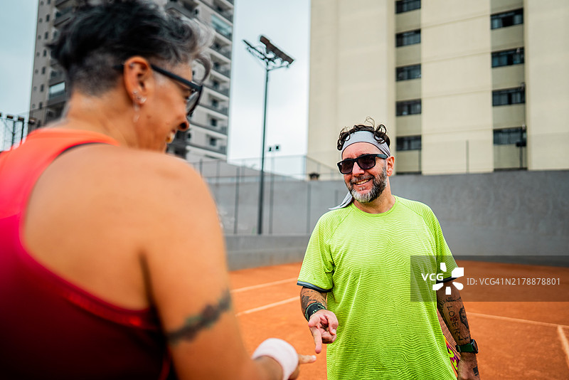 网球运动员在网球场上与另一名运动员玩剪刀石头布以开始比赛图片素材