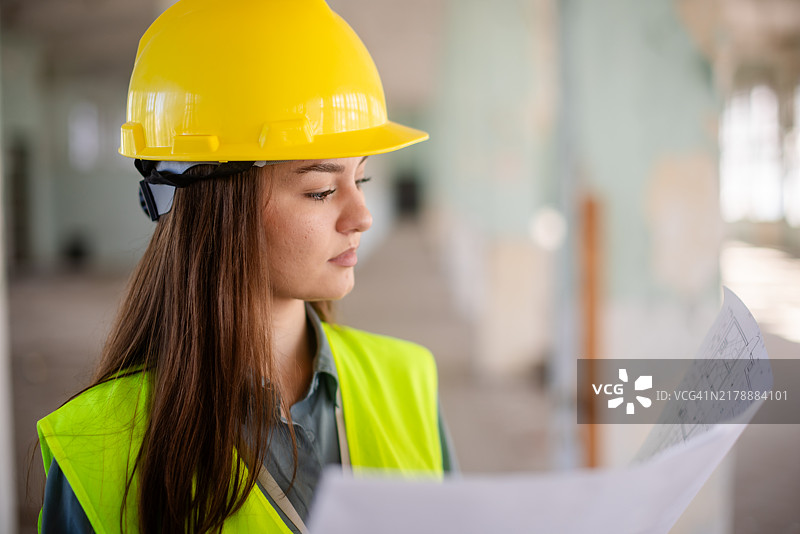 年轻工程师戴着安全帽研究建筑图纸图片素材