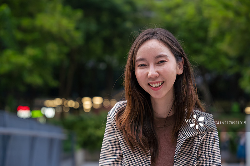 以绿色城市为背景的年轻女商人肖像图片素材