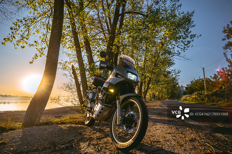 乌克兰赫梅利尼茨基，2023年9月10日：本田Transalp PD06 xl600摩托车，停在路边的旅游摩托车，可欣赏树木和日落景色，秋日温暖的黄色图片素材