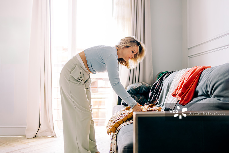 中年女性在家整理衣柜并试穿衣服图片素材