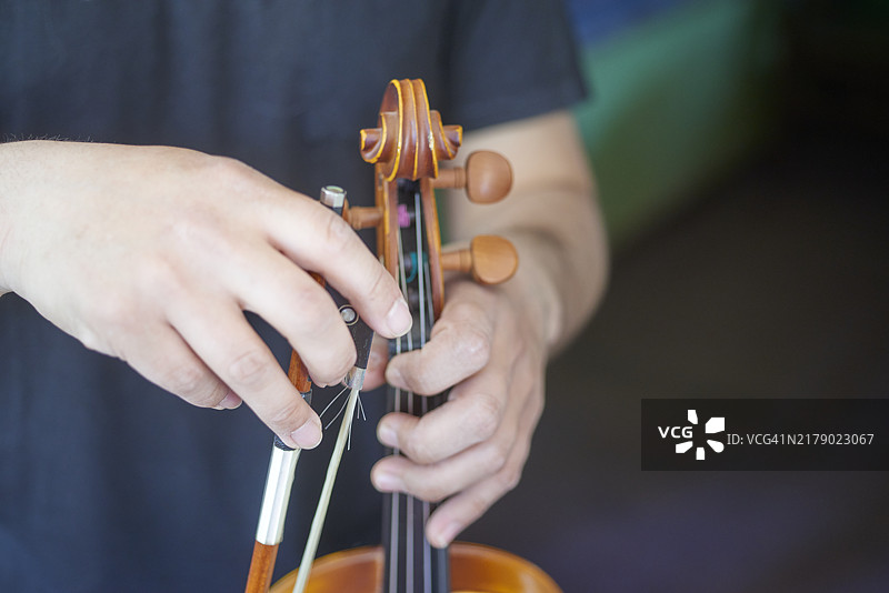 音乐家调整小提琴弓和琴身图片素材