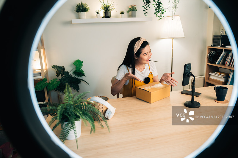 居家直播开箱的休闲装女人（带手机三脚架和环形灯）图片素材