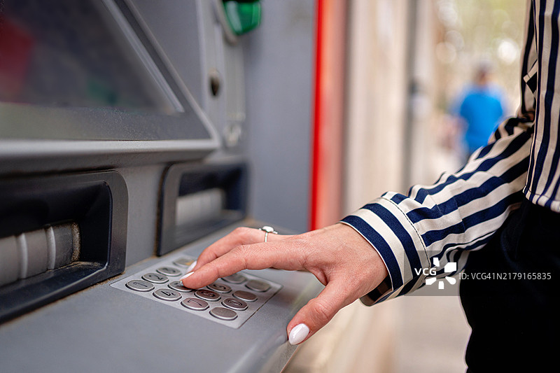 一位年轻女士在西班牙马略卡岛帕尔马的ATM机上取款图片素材