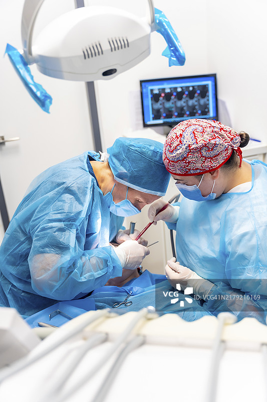 身穿蓝色手术服的医生为病人进行复杂的手术，扁平风格图片素材