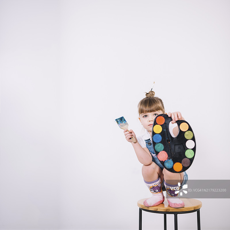 小女孩坐在椅子上拿着调色板画笔图片素材