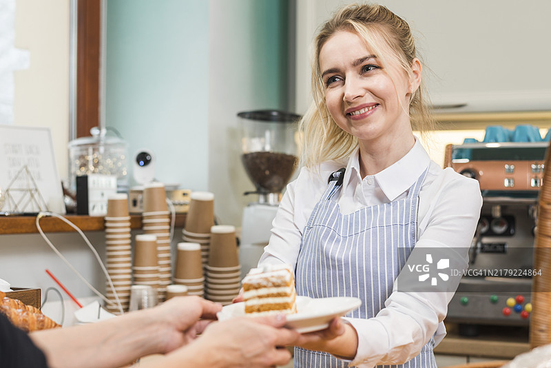 微笑的女面包师为顾客提供糕点蛋糕图片素材