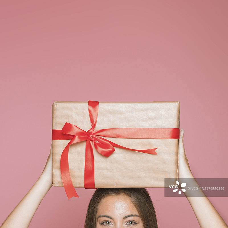 女人手持包装礼盒，粉色背景图片素材