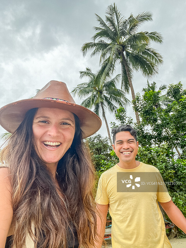 在热带海滩上自拍的不同微笑情侣图片素材