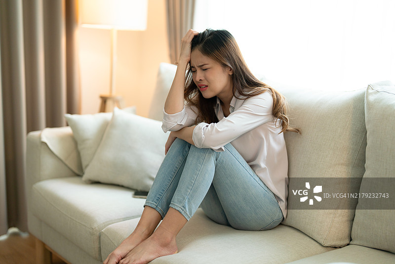 痛苦地坐在沙发上的沮丧女人图片素材