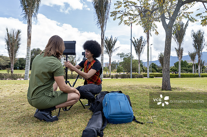 两位年轻网红在公园里准备他们的录音设备，为内容创作做准备。图片素材