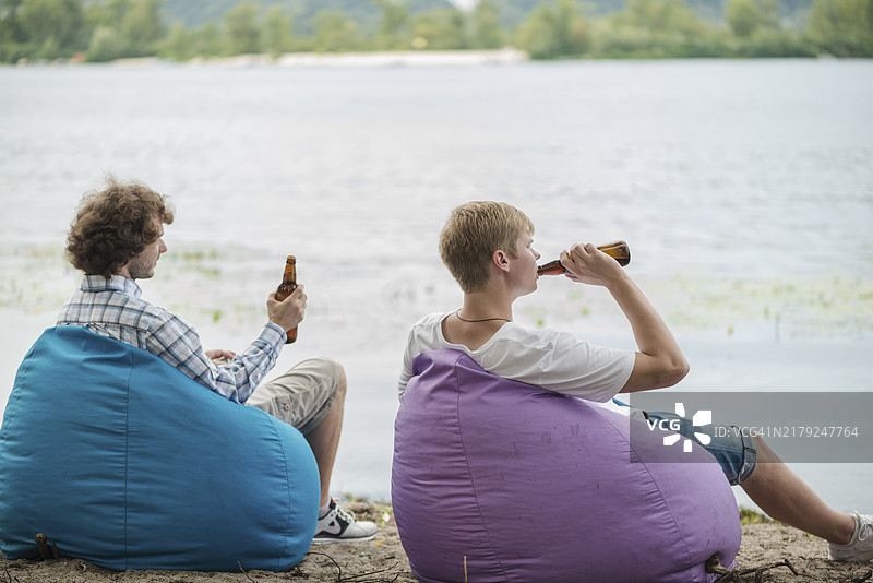 成年男人在水边放松喝啤酒图片素材