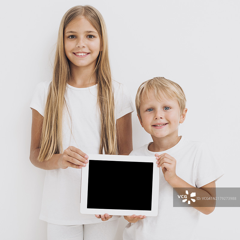 兄妹/姐弟拿着平板电脑模型正面照图片素材