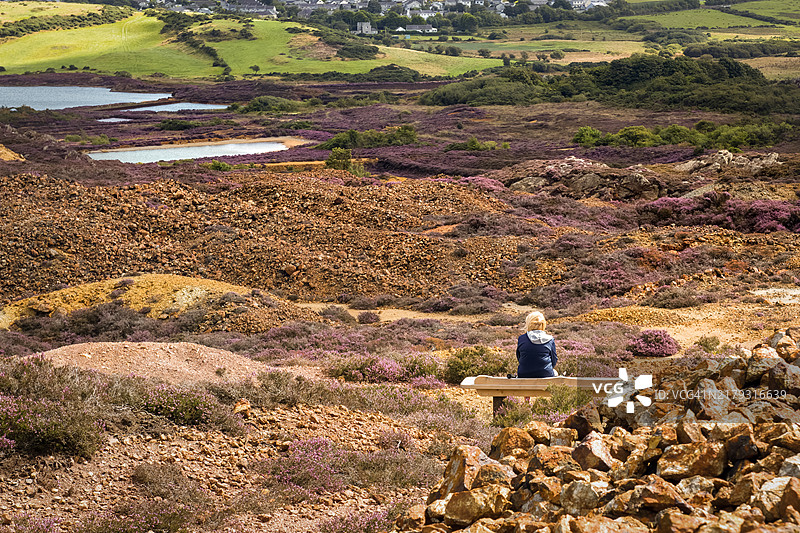 女人坐在座位上，眺望威尔士安格尔西岛的帕里斯山图片素材