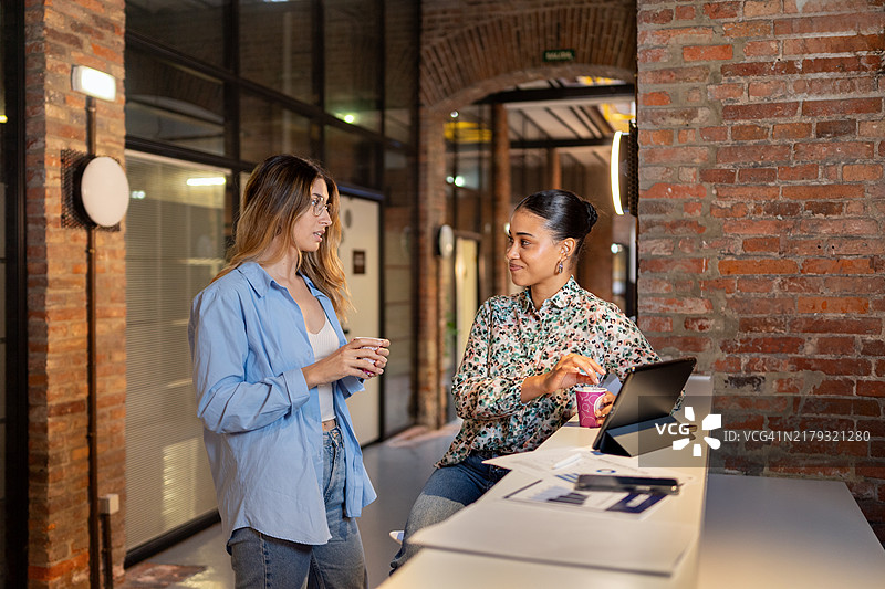 两位女商人在办公室走廊的办公桌旁举行非正式会议图片素材
