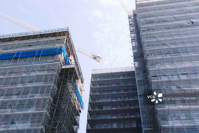 在带有脚手架的现代建筑上工作的建筑起重机图片素材