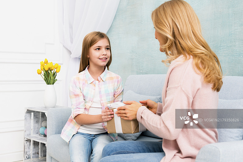 女儿给坐在沙发上的妈妈送礼盒图片素材