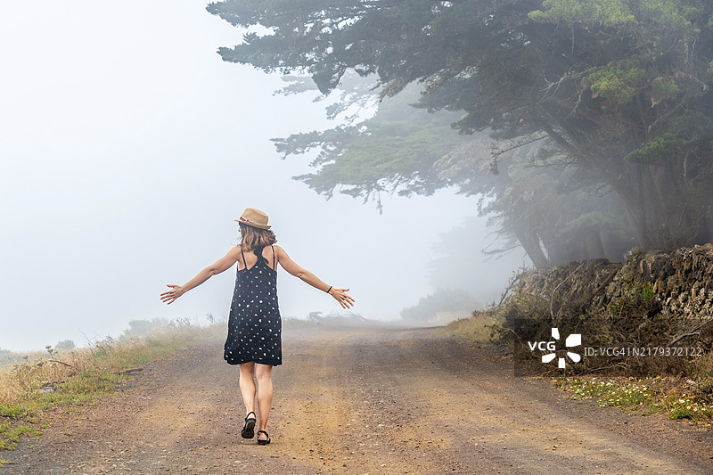 女游客走在耶罗岛雾蒙蒙的杜松森林小路上图片素材