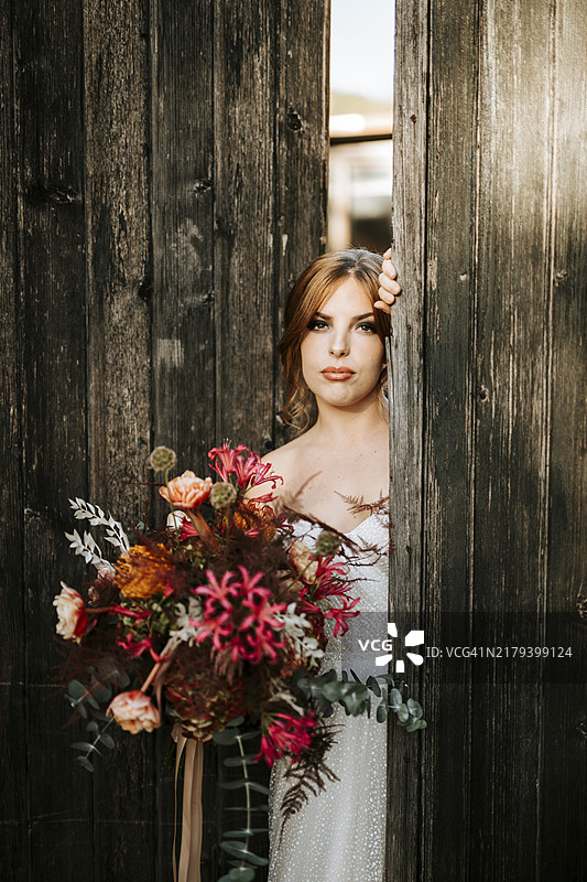 手捧花束、木门背景的美丽新娘图片素材