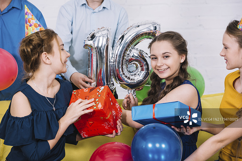 手持16岁生日气球礼物的女孩的微笑写真图片素材