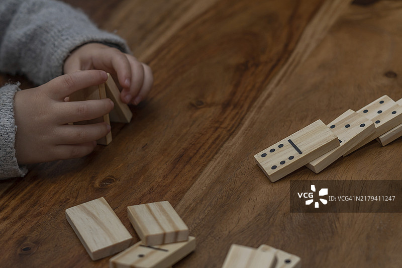 穿着灰色毛衣的孩子玩多米诺骨牌，焦点模糊图片素材