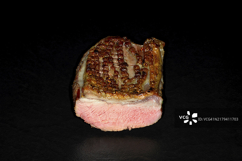 脆皮烤粉色羊鞍，黑色背景的影棚摄影图片素材