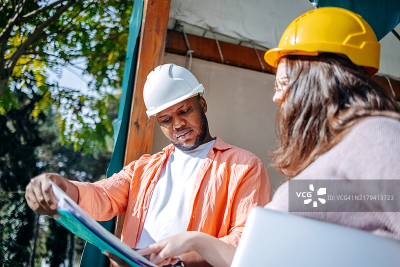 保险代理人在检查建筑损坏并查看施工图纸图片素材