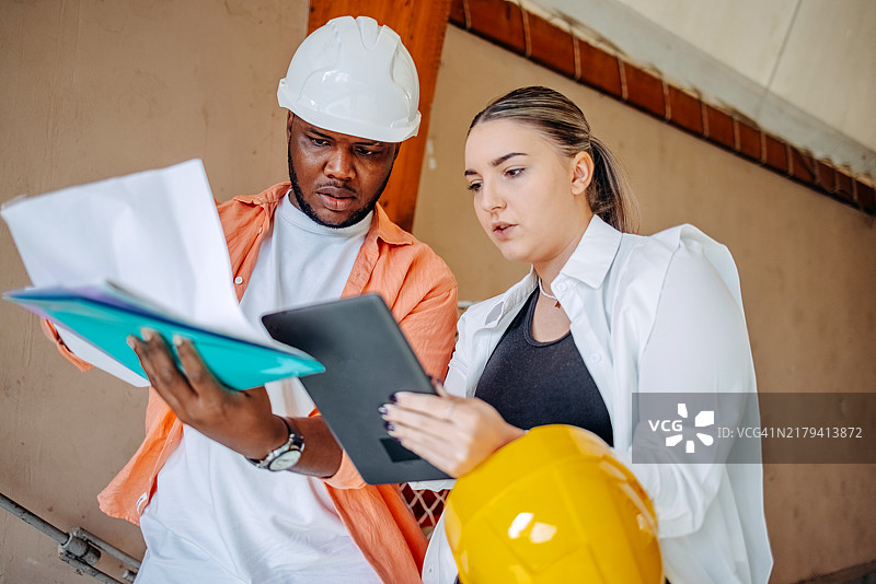 保险代理人在检查建筑损坏并查看施工图纸图片素材