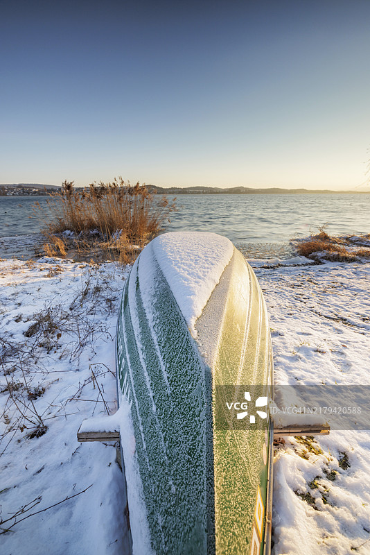 日出时分，康斯坦茨湖赖兴瑙岛尼德策尔湖岸边雪地上的倾覆船只，德国巴登-符腾堡图片素材