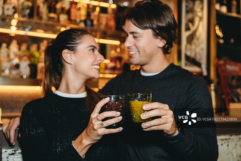 年轻情侣在酒吧微笑畅饮鸡尾酒图片素材