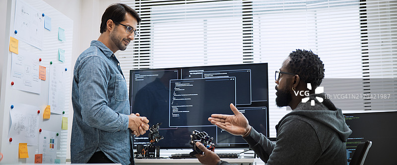 男性软件开发程序员合作编写机器人手臂程序图片素材