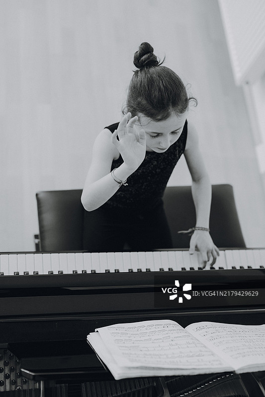 优雅女孩坐在音乐会大钢琴前弹钢琴图片素材