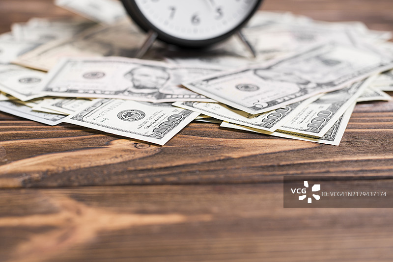 特写：闹钟和美元钞票在木桌上图片素材