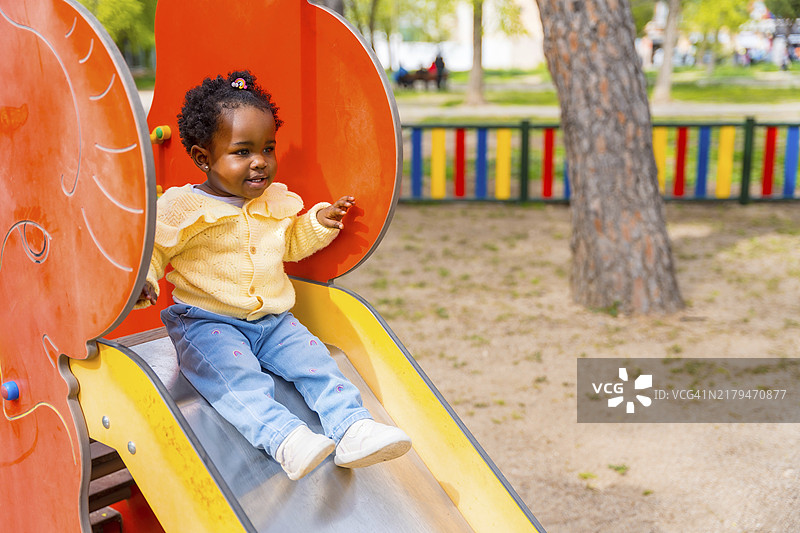 在公共游乐场玩滑梯的非洲女孩图片素材