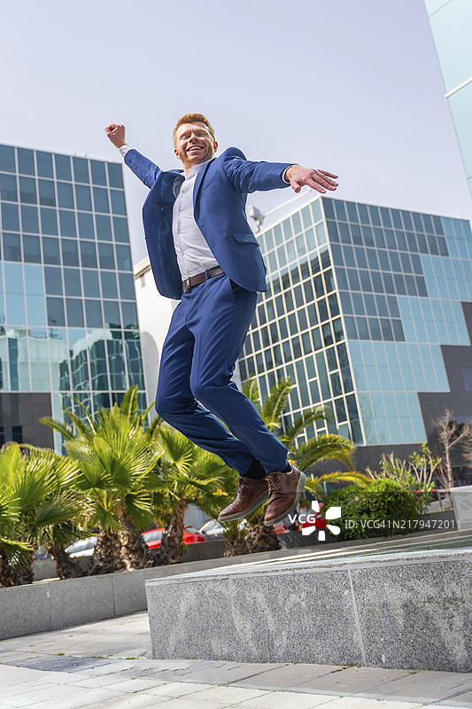 金融大厦旁快乐跳跃的商人竖版照片图片素材