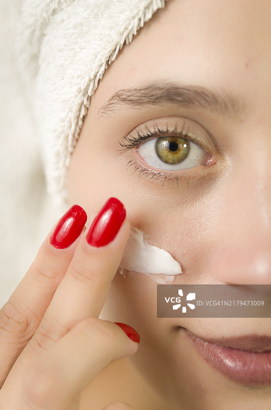 水润呵护：年轻女性健康肌肤涂抹护肤品特写图片素材