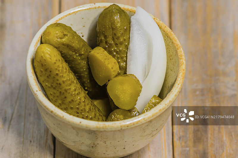 小碗腌黄瓜和洋葱放在木桌面上特写图片素材